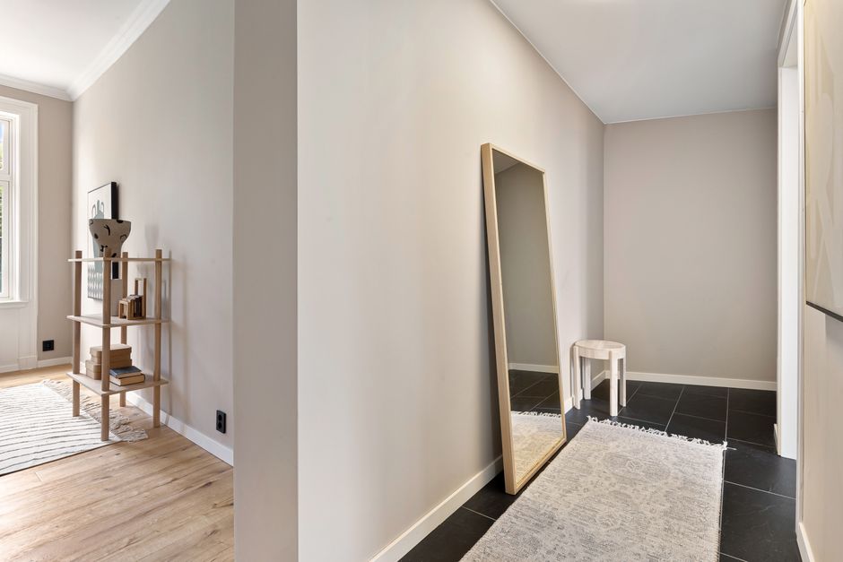 Clean modern hallway interior featuring a tall mirror, simple shelf, and natural light.
